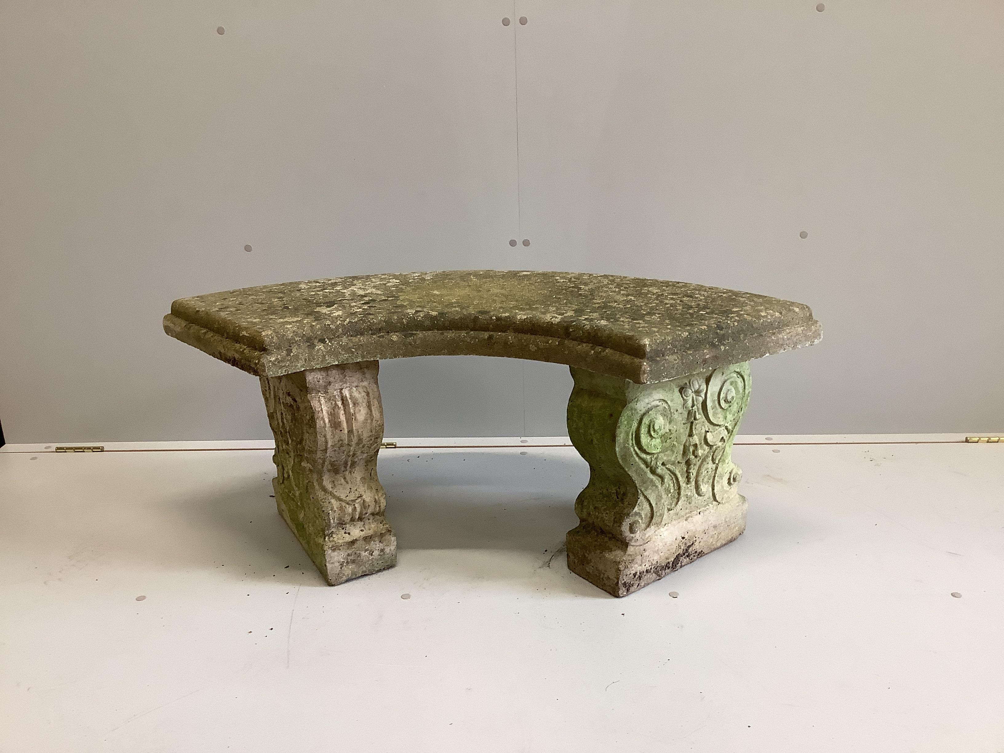 A weathered reconstituted stone curved garden bench, width 110cm, depth 48cm, height 45cm